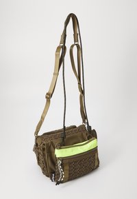 Olivengrønn veske med justerbare stropper, med en vevet tekstur og en frontlomme med en lys grønn glidelås. Kompakt og multifunksjonell design.