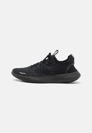 Des chaussures de sport noires avec une tige en tricot texturé et une semelle flexible. Les caractéristiques incluent un système de laçage et une languette au talon.