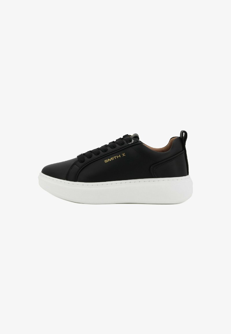 Sneaker in pelle nera con suola in gomma bianca, punta rotonda, chiusura con lacci e dettaglio del logo dorato di lato. Superfici testurizzate con una finitura liscia.