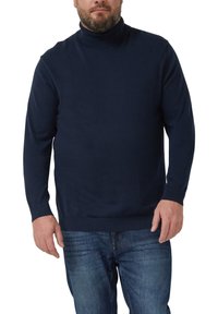 Marineblauer Rollkragenpullover aus weichem Stoff, mit einem gerippten Kragen und Bündchen, kombiniert mit blauen Jeans.