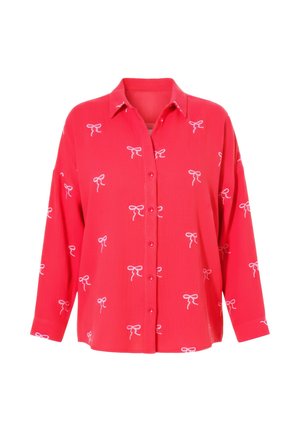 Blusa roja de manga larga con botones y patrones de lazos blancos distribuidos uniformemente por toda la tela, con cuello clásico y corte holgado.
