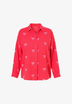 Blusa roja de manga larga con botones y patrones de lazos blancos distribuidos uniformemente por toda la tela, con cuello clásico y corte holgado.
