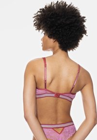 Pink lace bra with wide straps, horizontal striped details in a lighter shade, and a hook closure at the back. Soft texture, delicate design.