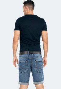 Navy t-shirt paired with rolled hem denim shorts. Features four pockets, contrast stitching, and a black belt for a casual look.