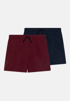 Red and navy swim shorts made of smooth fabric with an elastic waistband and black drawstring, featuring a simple, solid color design.