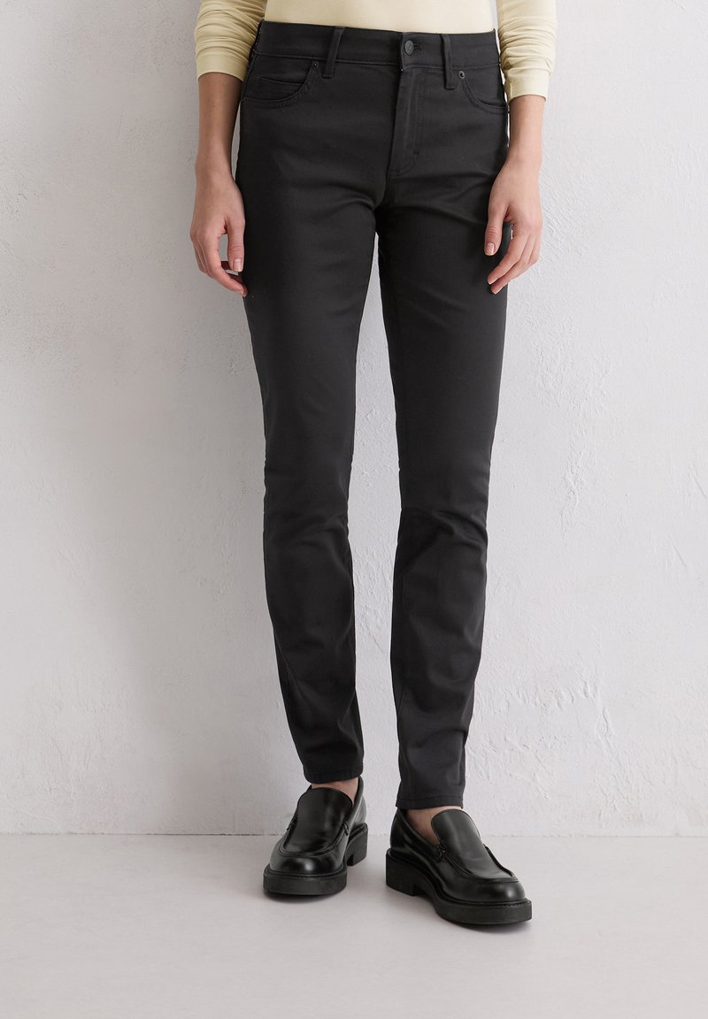 Zwarte fitted broek gemaakt van een katoenmix, met een klassiek vijfzakdesign en een gladde textuur. Gecombineerd met zwarte instappers.