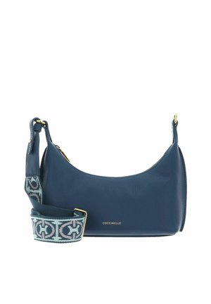 Sac à bandoulière en cuir bleu avec fermeture éclair dorée et sangle amovible à motifs, avec un petit logo doré "Coccinelle" sur le devant.