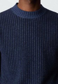 Maglione a coste navy con colletto a girocollo, caratterizzato da un motivo testurizzato e una superficie liscia. Progettato per una silhouette aderente.