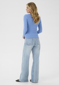Lichtblauwe geribbelde langemouwen top gecombineerd met lichte denim wijd uitlopende jeans. De outfit heeft een aansluitende silhouet en een minimalistisch ontwerp.