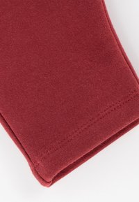 Burgundy cotton fabric with a soft texture, featuring a folded edge and subtle stitching detail along the hem.