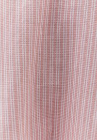 Tessuto leggero e strutturato con strisce alternate rosa e bianche, che offre una qualità morbida e traspirante. Motivo a griglia sottile su tutta la superficie.