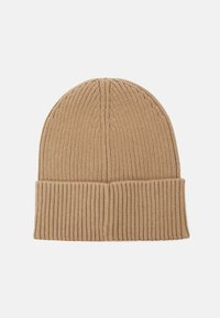 Gorro de punto en un color beige claro, con textura en relieve, un borde doblado y costuras verticales en la parte superior.