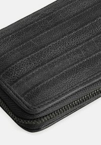 Zwart lederen portemonnee met een gestructureerde oppervlakte, voorzien van een ritssluiter en verticale stiksels voor extra detail.