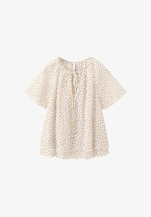 Blouse crème à manches courtes avec pois noirs, encolure ronde et détail noué devant, coupe ample, tissu léger.