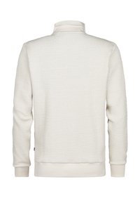 Svetle béžový svetr s texturovaným designem ve vaflovém pletení. Má vysoký límec a žebrované manžety a lem, které zajišťují těsné uchycení.