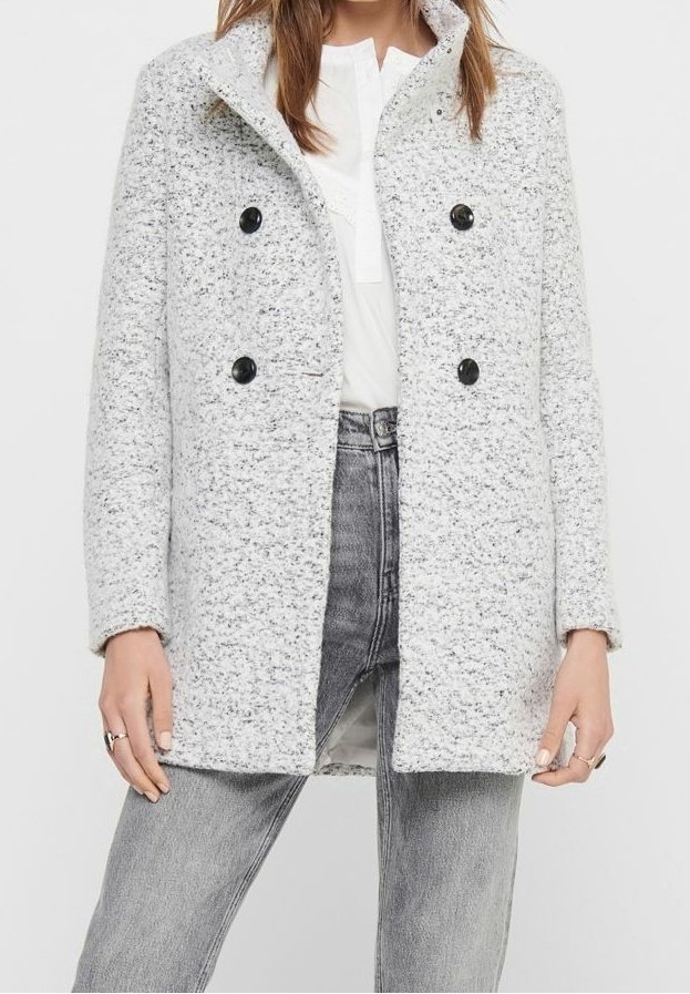 Abrigo de lana gris jaspeado con cuello, diseño cruzado y botones negros, combinado con una camiseta blanca y vaqueros grises.