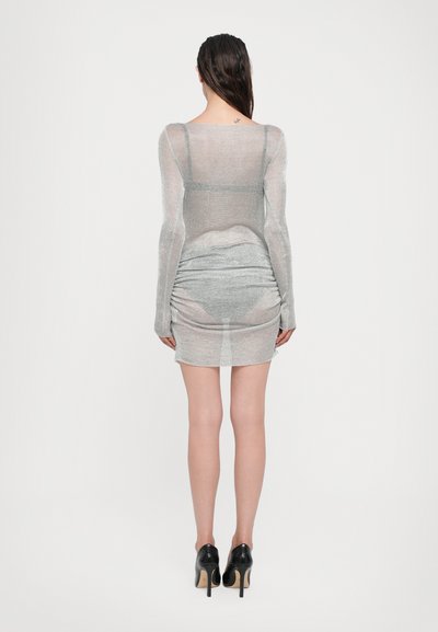 Vestido ajustado de manga larga en color plata, confeccionado con tela transparente. Presenta detalles fruncidos en la parte trasera y un dobladillo a la altura de la rodilla.