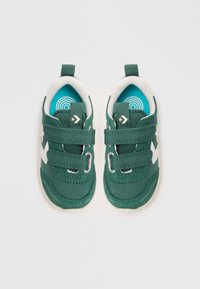 Sneakers in tessuto verde con accenti bianchi, strap in velcro, soletta turchese rotonda e suole in gomma. Presentano un logo a forma di stella sul lato.