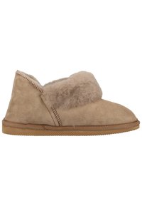 Chausson en suède beige avec un doux revers en shearling, bout arrondi et semelle en caoutchouc texturé. Présente des coutures décoratives le long du bord.