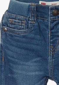 Smala jeans i ljusblå denim med ribbad midjeband, med stickade detaljer, en framficka och en knappknäppning.