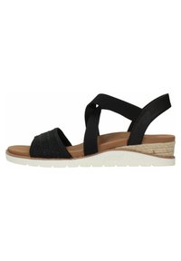 Sandalias de cuña negras con parte superior de tejido trenzado, correas elásticas cruzadas, plantilla beige y suela blanca de goma texturizada.