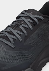 Κοντινό πλάνο του σκούρου γκρι παπουτσιού πεζοπορίας The North Face Enduris 4 με υφή από πλεκτό δίχτυ, χονδρά πλεγμένα κορδόνια και επενδεδυμένη σόλα.