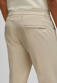 Beiga shorts med bakfickor, en mjuk textur och en logotyp på höger ficka. Utformade med bälteshällor och en skräddarsydd passform.