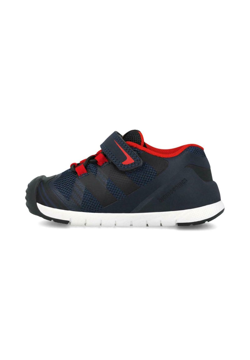 Zapatilla deportiva con parte superior de malla en azul marino y negro con acentos rojos, correa ajustable y suela de goma blanca curvada con agarre texturizado.