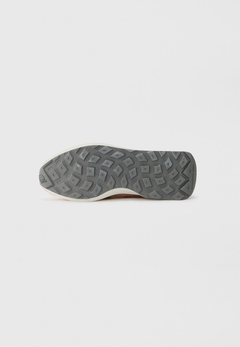Semelle de sneaker en caoutchouc avec un motif texturé gris, dotée d'un bord blanc en bas et d'une marque au niveau du talon.