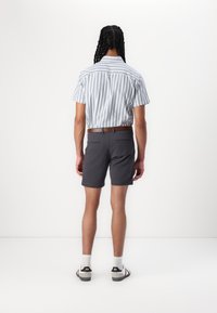 Short-sleeve striped shirt in blue and white, paired with dark gray shorts. Brown belt and black sandals complete the look.
