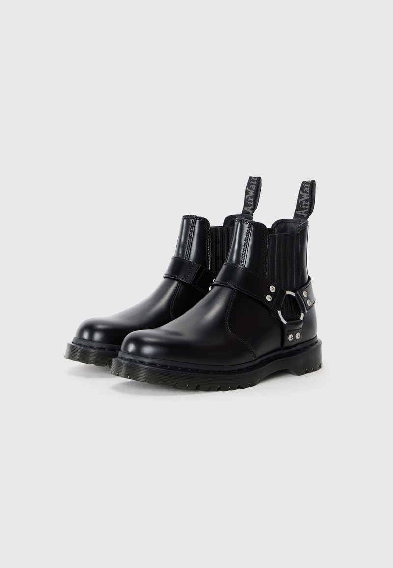 Bottines en cuir noir avec des panneaux élastiques sur les côtés, accents en boucle en argent et semelles en caoutchouc texturé. Comprend des languettes pour un enfilage facile.