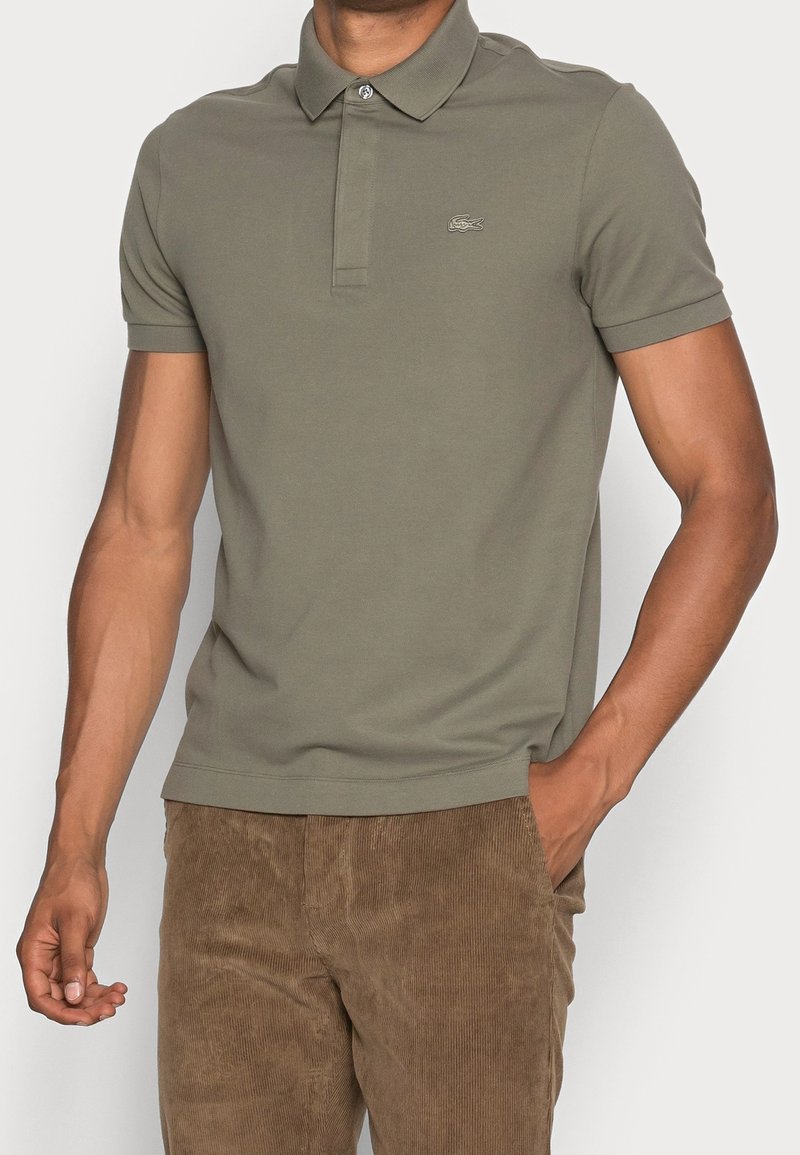 Polo-shirt vert olive, à manches courtes, design col, forme ajustée, avec un petit logo sur la poitrine, en coton doux.