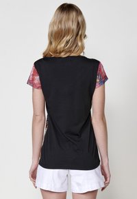 Camiseta negra con mangas cortas y estampadas en tonos rojo y azul, textura suave y corte recto en el dobladillo.