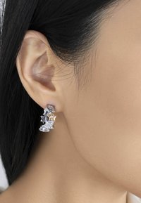 Pendientes de estrella de tres niveles que presentan metal en tonos plateado y dorado, con un acento de rhinestone brillante en la estrella inferior.