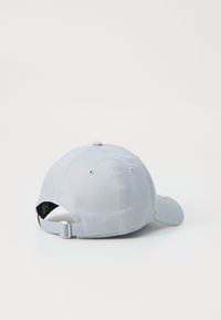 Gorra de béisbol gris claro hecha de algodón, con visera curvada, correa trasera ajustable y pequeños orificios de ventilación a lo largo del costado.