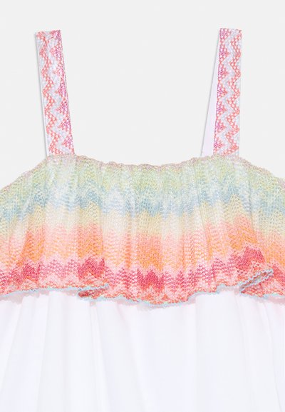 Elastični vrh z večbarvnimi zigzag smocki v pastelnih odtenkih, ki ima lahke naramnice in preprosto belo krilo spodaj.