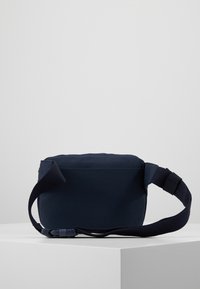 Borsa a spalla in tessuto blu navy con forma rettangolare, tracolla regolabile e superficie liscia. Presenta una chiusura laterale a fibbia e un design minimalista.