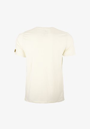 Camiseta de algodón color crema con mangas cortas, cuello redondo y un pequeño parche en la manga izquierda con el logo de la marca. Diseño liso en la parte posterior.