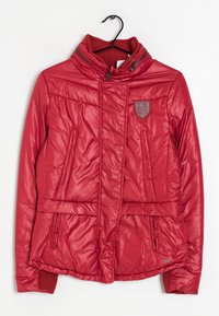 Rød polstret jakke med højt krave, lynlås i front, sidelommer, ribbede manchetter og et logo patch på venstre bryst. Glat, skinnende tekstur.