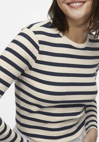 Randig stickad tröja i kräm- och marinblå färger, ribbad textur, rund halsringning och långa ärmar med kontrasterande ränder.