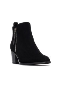 Botines de ante negros con tacón cónico, detalle de cremallera lateral y textura suave. Punta redonda y un diseño de tacón sutil.