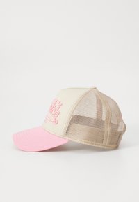 Beige caps med en rosa brem, med netting på sidene og baksiden. Forsiden har brodert rosa tekst. Buet brem og justerbar stropp.