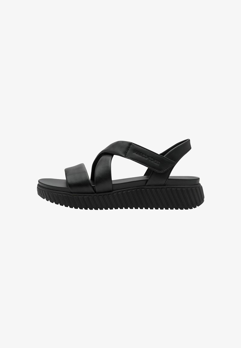 Sandale noire avec des lanières en cuir croisées et une semelle en caoutchouc texturée. Présente une plateforme basse et un design minimaliste.