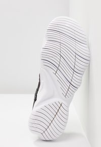 Czarny sneaker z teksturowaną cholewką i wyraźną białą, wzorzystą podeszwą. Posiada zieloną metkę po boku.