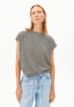 T-shirt à rayures noires et blanches avec un col rond, des manches courtes et une coupe décontractée, associée à un jean en denim bleu clair.