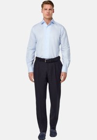 Chemise à rayures bleu clair avec fermeture à boutons, associée à un pantalon bleu marine et une ceinture noire texturée. Portée avec des chaussures navy.