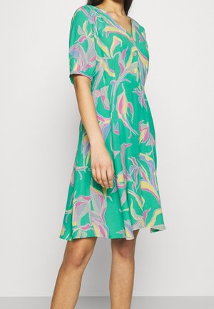 Robe verte à manches courtes avec un décolleté en V, ornée d'un motif de feuilles colorées en rose, jaune et bleu. Tissu doux avec une silhouette fluide.