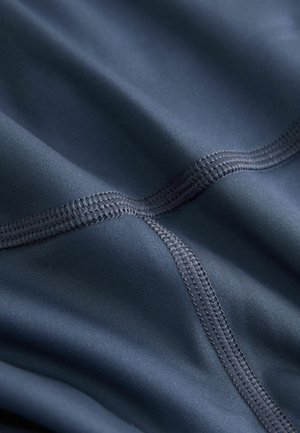 Marineblauer Stoff mit glatter, matter Oberfläche. Mit kontrastierenden Nähten im Karomuster, die die weiche Textur des Materials betonen.