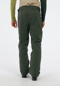 Groene waterdichte broek met een relaxte pasvorm. Kenmerken zijn versterkte knieën, ritsmanchetten en een verstelbare tailleband voor comfort en mobiliteit.