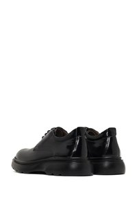 Chaussures en cuir noir avec une finition brillante, bout rond et semelle en caoutchouc épaisse. Présentent des lacets et des détails de couture subtils sur les côtés.